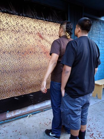 Still from performance accompanied by Alberto Esparza jaguar mat, (el hoyo), 2013, gold leafed jaguar-printed fabric, black trash bags, main entrance door to gallery, artist's blood. Rafael Esparza