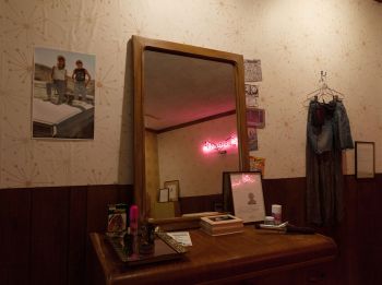 Installation view (2) of Exit Strategies; 2018; neon sign, carpet, wallpaper, wood laminate, latex paint, acquired furniture and beauty products, framed documents: acetone transfers on archival paper Yasmine Diaz